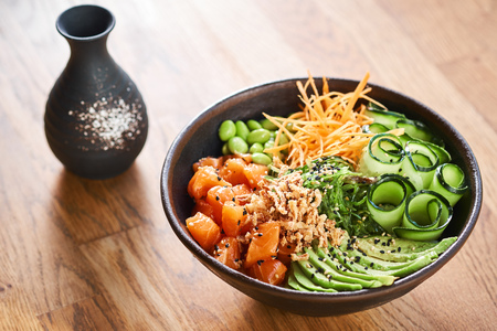 Poke bowl with sake on wooden table. Traditional Hawaiian dish and Japenese alcoholic beverage.の写真素材
