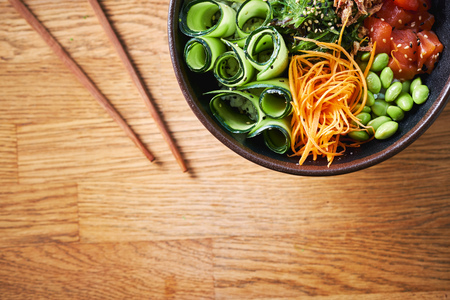 Top view of a poke bowl with chopsticks on wooden background. Traditional Hawaiian dish. Native Hawaiian and Japanese cuisine. Copy space.の写真素材