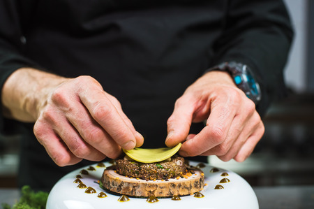 Close-up of male hands cooking modern molecular dish. Dark background. Molecular cuisineの写真素材