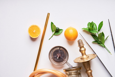 Shisha hookah details with orange and green leaves on white background. Copy space.