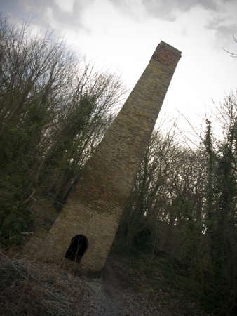 Old Brick Mill Chimney in Winter with Grey Skyの写真素材