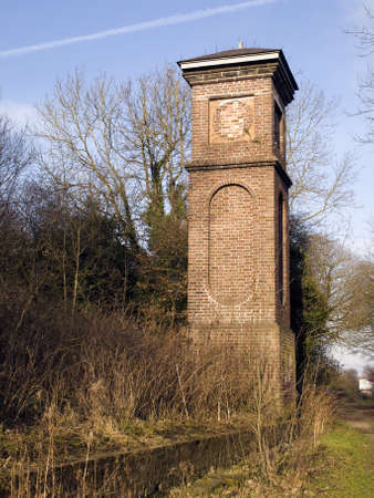 old Brick Clocktower  building in overgrown Grassの写真素材