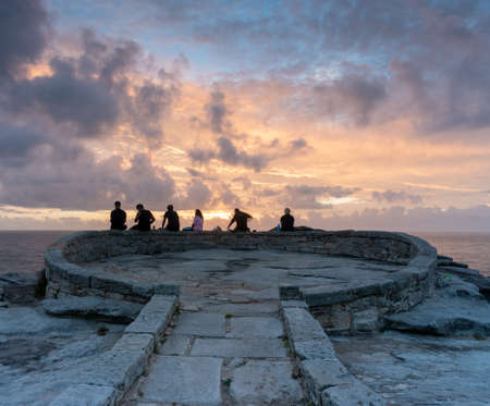 many people sitting and staring at the sunrise at south bondi rockの写真素材