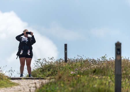 woman taking a photo on her phone with a baby in the carrier.の写真素材