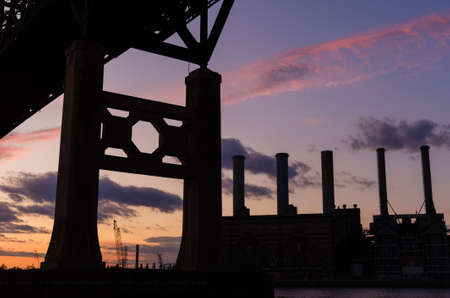 Bridge and industrial area silhouetted at sunsetのeditorial素材