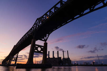 Bridge and industrial area silhouetted at sunsetのeditorial素材