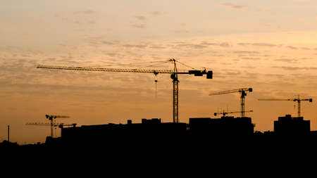 Tower cranes on a construction site behind buildingsの写真素材