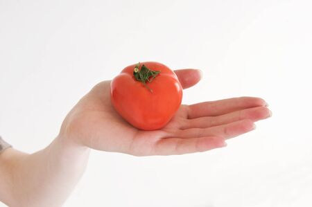 Young girl with fresh red tomato in hand.の写真素材