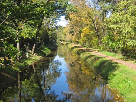 Canal in rural village in autumn with bicycle path.の写真素材