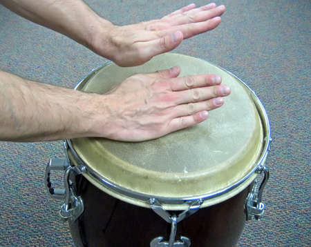 Two hands playing a conga drum; carpet background.の写真素材