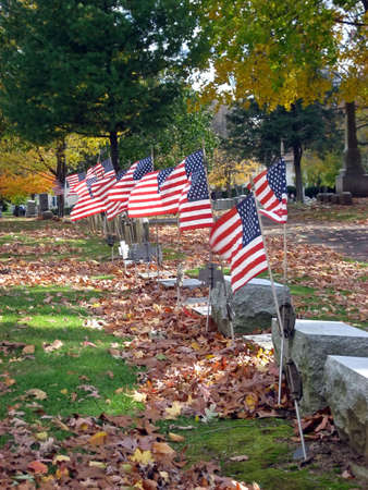 Headstones and Flags in a Cemetery in Autumnの写真素材