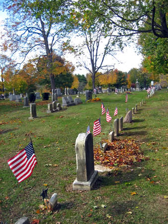 Gravestones with American Flags in a Cemetery in Autumnの写真素材