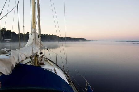 sailing yacht at anchor on river at dawnの写真素材