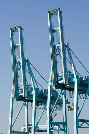 pair of container cranes in port against blue sky