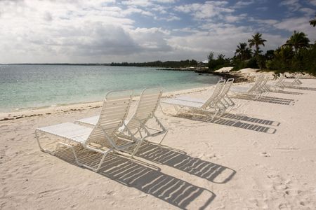 line of loungers casting a shadow on the sandy beach