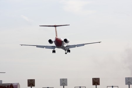 twin engine jet aircraft passing over fence during landing approach