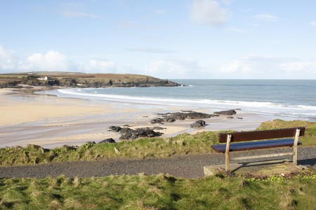 bench seat overlooking a deserted beach in winter sunshineの写真素材