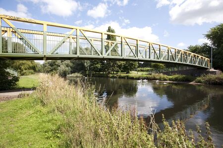 yellow and green footbridge over calm riverの写真素材