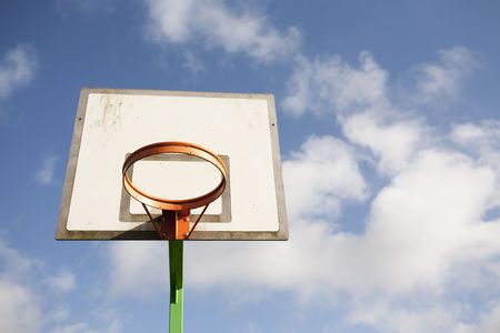 basketball hoop against a blue sky and white clouds
