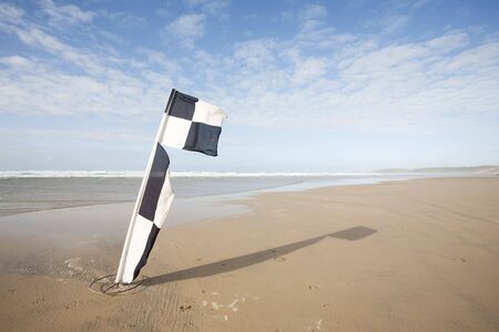 swimming warning flags blowing in the wind on a beachの写真素材
