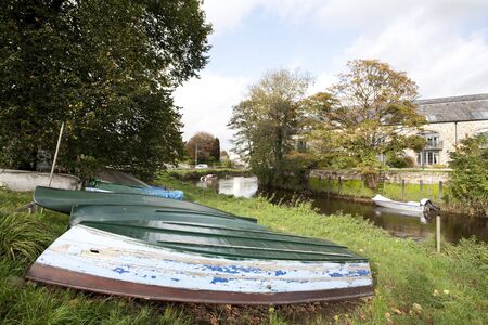 upturned boats on the grassy banks of a river