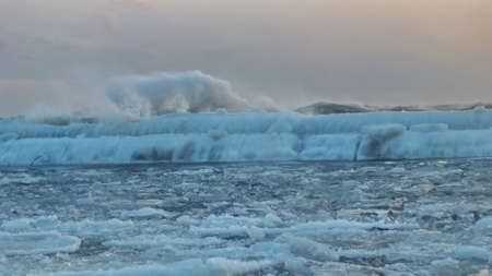 Waves with floating ice break against the shoreline in Toronto, Ontario, Canada, during a winter storm.の写真素材