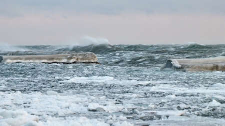 Waves with floating ice break against the shoreline in Toronto, Ontario, Canada, during a winter storm.の写真素材