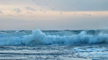 Waves with floating ice break against the shoreline in Toronto, Ontario, Canada, during a winter storm.の写真素材