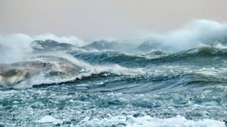 Waves with floating ice break against the shoreline in Toronto, Ontario, Canada, during a winter storm.の写真素材