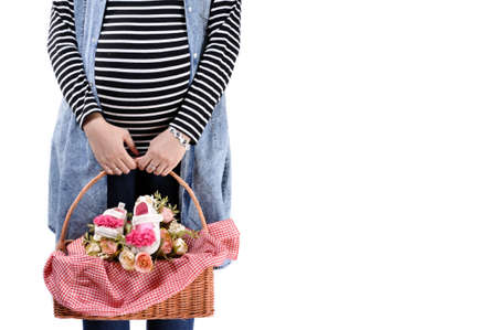 A pregnant woman is carrying a basket of flowers and baby shoesの写真素材