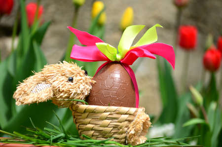 chocolate Easter egg with pink ribbon in a tulips garden