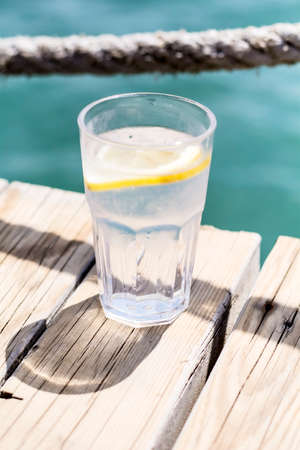 Gin tonic cocktail with lemon slice on a sea backgroundの写真素材