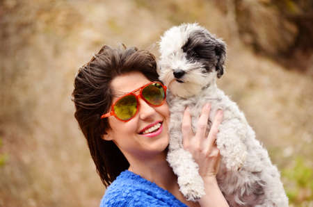 smiling woman hugging  her small poodle dog outdoor