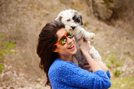 smiling woman hugging  her small poodle dog outdoor