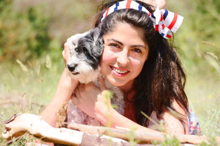 smiling woman laying and  hugging  her small poodle dog outdoorの写真素材