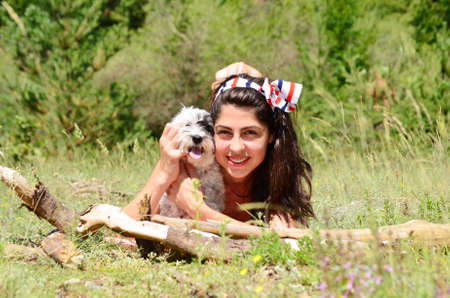 smiling woman laying and  hugging  her small poodle dog outdoorの写真素材