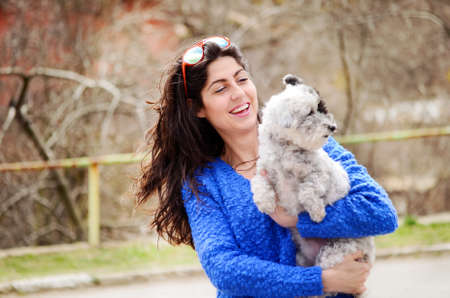 smiling woman hugging  her small poodle dog outdoorの写真素材