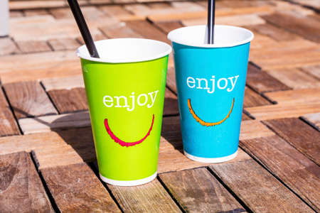 Green and blue paper coffee cups with straws and enjoy signの写真素材