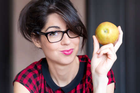 Happy young woman eating apple indoor.Healthy livingの写真素材