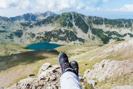 Legs with hiking boots of hiker woman traveler sitting in the summer mountain . Freedom conceptの写真素材