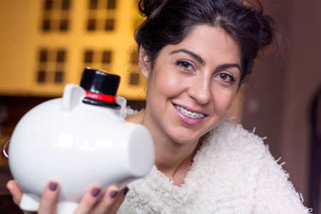 Woman Putting money In Piggy Bank, Indoorsの写真素材
