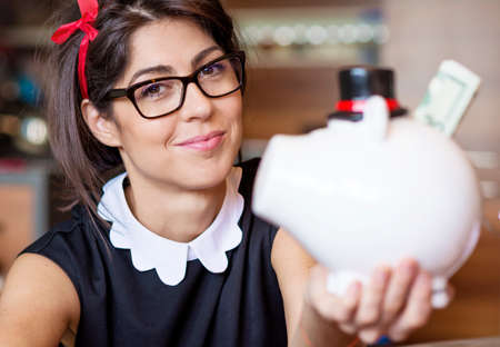 Woman Putting money In Piggy Bank, Indoorsの写真素材
