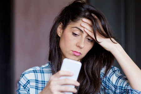 Portrait of young sad annoyed woman, receiving bad smsの写真素材