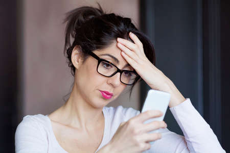 Portrait of young sad annoyed woman, receiving bad smsの写真素材