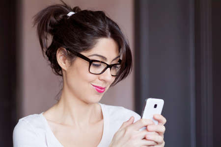 Portrait of young smiling woman receiving funny messageの写真素材