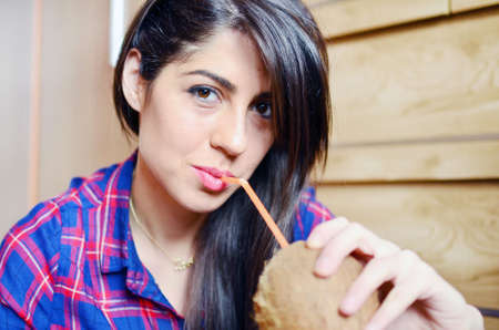 beautiful young woman drinking fresh coconut juice with a strawの写真素材