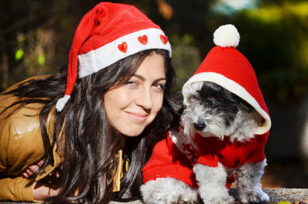 beautiful young woman with her small poodle dog dressed with red christmas hats.Winter holidaysの写真素材