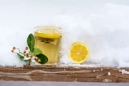 mug of tea with lemon slice wrapped in a knitted scarf on the snowの写真素材