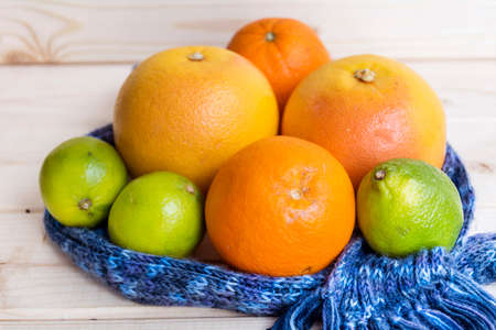 orange fruits,grapefruits and limes wrapped in a  scarf on a wooden background.Winter fruit dietの写真素材