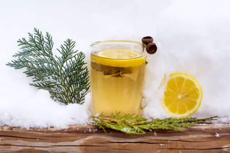 glass cup of tea with lemon slice wrapped in a knitted scarf on the snowの写真素材